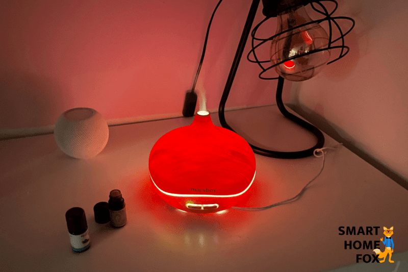 Ein Aroma-Diffuser steht auf einem Regal und ein feiner Nebelstrahl tritt aus dem Modell und befeuchtet die Luft.